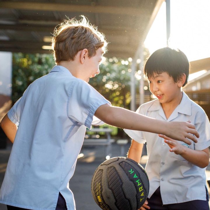 Two little boys playing basketball in the sun at Camp Australia