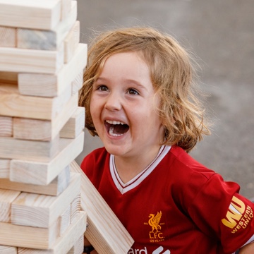 little boy with a surprised expression playing a game of Jenga at Camp Australia