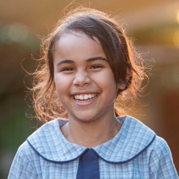 Headshot of a little brunette girl smiling into the camera at Camp Australia