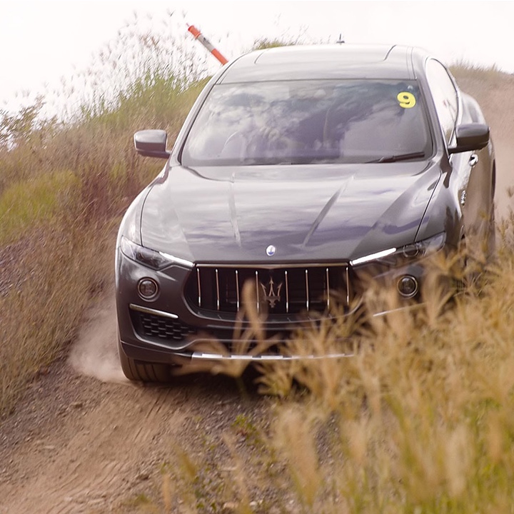 Luxury black Maserati SUV driving downhill