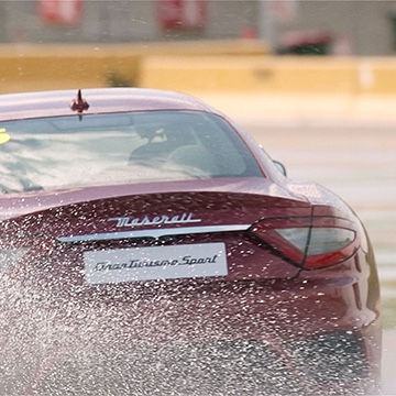 Behind shot of a red Maserati luxury sports car driving through water
