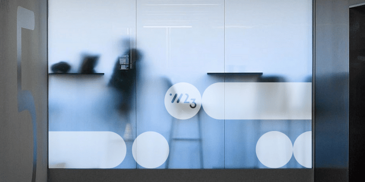 W23 rebrand graphic device mocked up on frosted office wall.